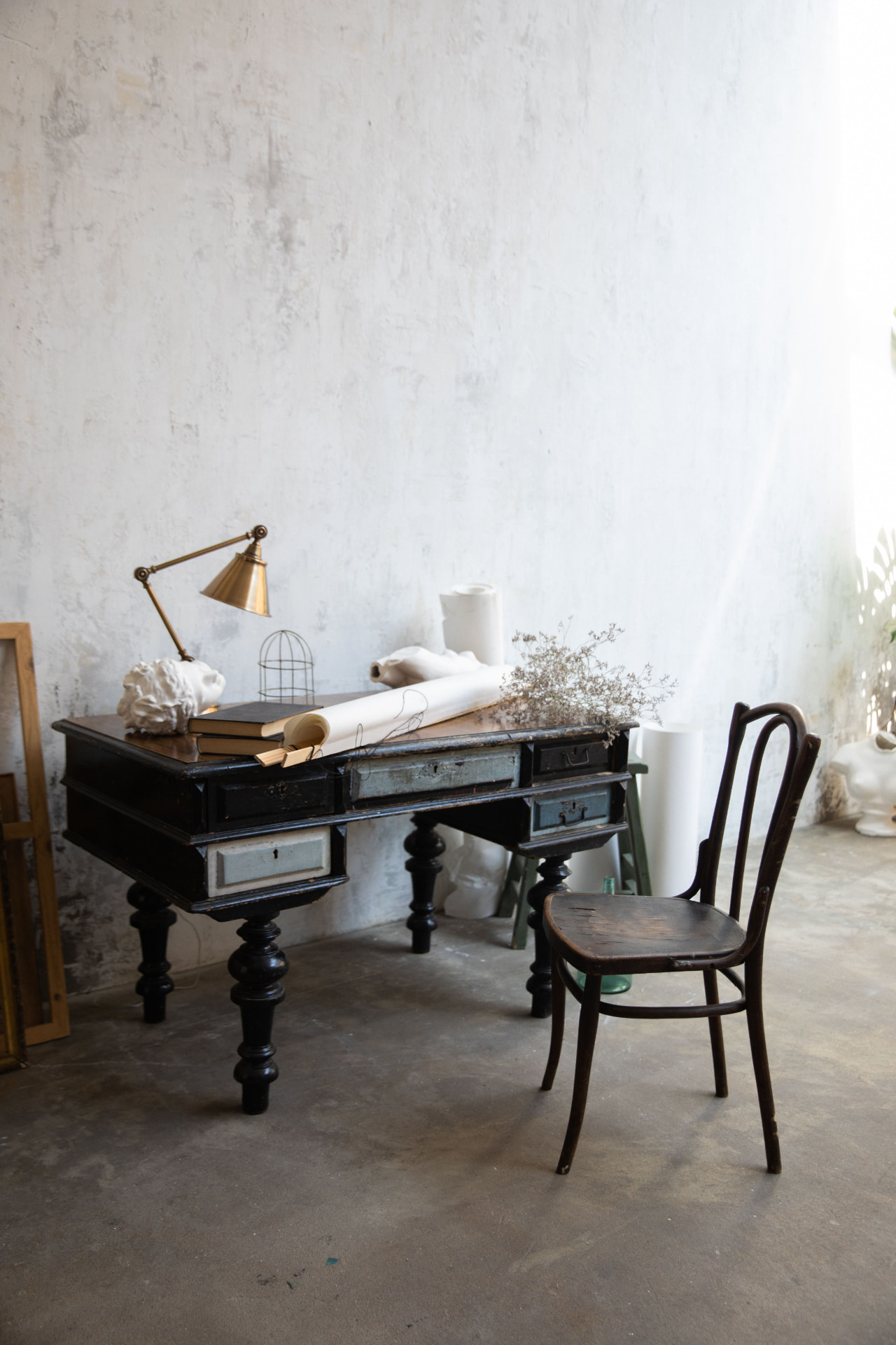 A writer's vintage desk with a brass lamp and bentwood chair